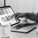 Black and white photo of a person shopping online on a laptop, highlighting e-commerce technology.
