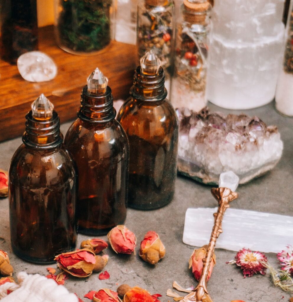 Aesthetic arrangement of brown bottles, dried rose petals, and crystals for aromatherapy.