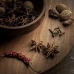 Artistic close-up of whole spices on a wooden board, showcasing star anise, nutmegs, and more.